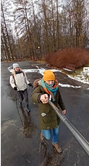 Tandem w uprzęży, przewodnik idzie z przodu ostrzegając przed przeszkodami na trasie, osoba niewidoma/ niedowidząca ma kijki poza ramą stworzoną z liny (uprzęży)