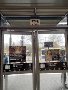 drzwi galerii krakowskiej, nad nimi widoczna nalepka kodu NaviWay