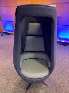 fotel wygłuszający dźwięki, wykonany z miękkiego materiału, który sięga ponad głowę, gdy siedzi się na fotelu